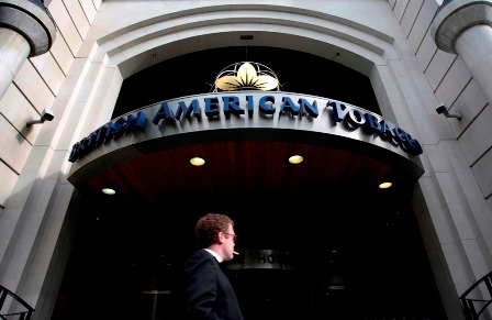 A man smokes as he passes the British American Tobacco offices in London May 6, 2009. British American Tobacco Plc, the world's second-biggest cigarette maker, on Wednesday reported flat underlying first-quarter cigarette sales volume and said trading became tougher during the quarter.   REUTERS/Luke MacGregor  (BRITAIN BUSINESS) - RTXES12