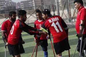 (180311) -- CAIRO, March 11, 2018 (Xinhua) -- A member of the "Miracle Team" puts the captain band on Mahmoud Abdo's arm before a training session in the pitch of El Salam youth center on the outskirts of the capital Cairo, Egypt on March 9, 2018. Carrying crutches, a group of 40 Egyptian one-legged soccer players have recently formed their "Miracle Team" that aspires to start league for disabled footballers in the country and dreams of joining the amputee football world cup one day. (Xinhua/Ahmed Gomaa)